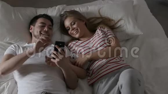 年轻夫妇在卧室里用手机上网视频的预览图