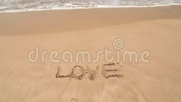 海浪覆盖着爱这个词写在沙滩上视频的预览图