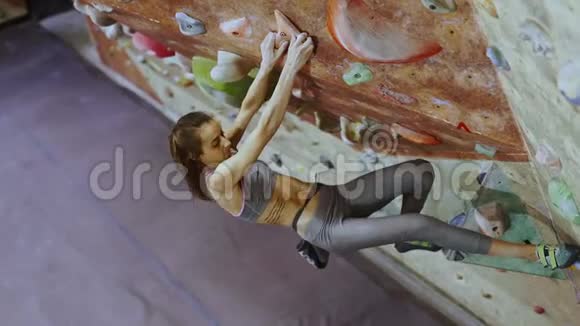 年轻女子攀岩者正在攀岩健身房里攀岩苗条漂亮的女人在室内攀岩墙上锻炼视频的预览图