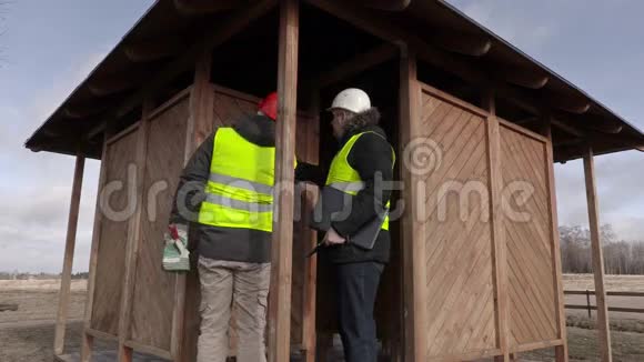 建筑工程师在木制建筑附近使用智能手机视频的预览图