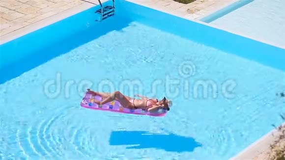 大泳池里穿比基尼充气床垫的年轻女子视频的预览图