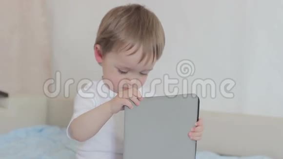 小男孩在床上玩平板电脑视频的预览图