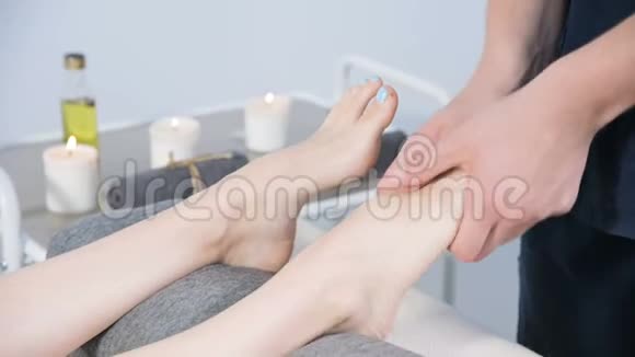 一名男性理疗师在美容和健康水疗中心为一名年轻女孩做足底按摩足部和身体护理视频的预览图
