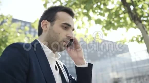 年轻英俊的商人在城里用手机聊天视频的预览图