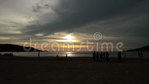 日落时人们在夏日海滩散步的剪影视频的预览图