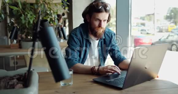 男子在咖啡厅的笔记本电脑上工作视频的预览图