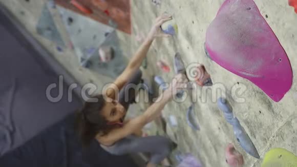 年轻女子攀岩者正在攀岩健身房里攀岩苗条美丽的女人在室内攀岩墙上锻炼视频的预览图