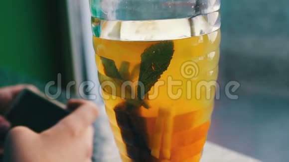一个男孩在柠檬茶和肉桂旁边的咖啡馆玩智能手机视频的预览图