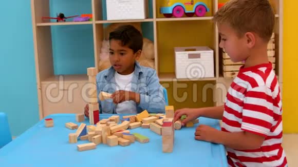 可爱的小男孩在教室的桌子上玩积木视频的预览图