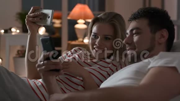 年轻家庭在卧室里用手机上网视频的预览图