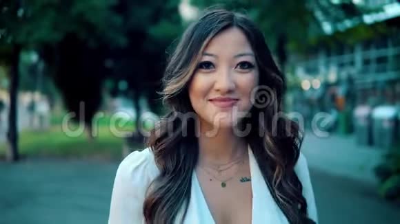 美丽的亚洲女孩穿着白色连衣裙在公园里微笑视频的预览图