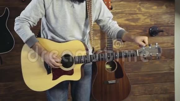 把男人的双手合拢调好一把吉他的慢动作视频的预览图