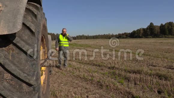 农夫在拖拉机轮边打电话视频的预览图