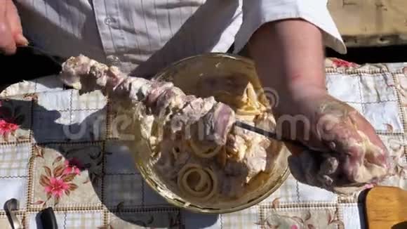 胖子把腌制的生肉放在一个绞架上以求在大自然上做一个ShishKebab视频的预览图