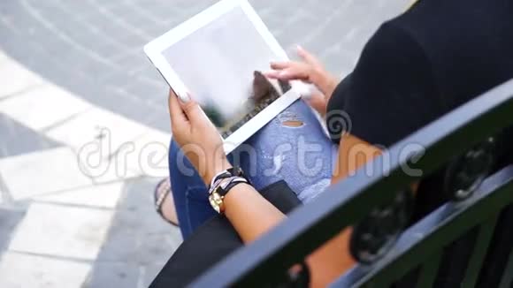 坐在城市公园里拿着平板电脑的年轻女子视频的预览图