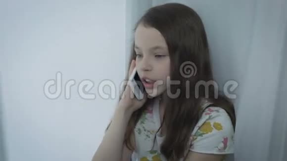 漂亮的小女孩在智能手机上情绪化说话视频的预览图