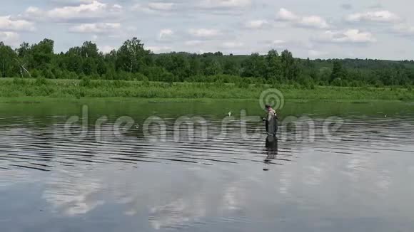 渔夫在一条平静的河里钓鱼穿着渔具的人在河里视频的预览图