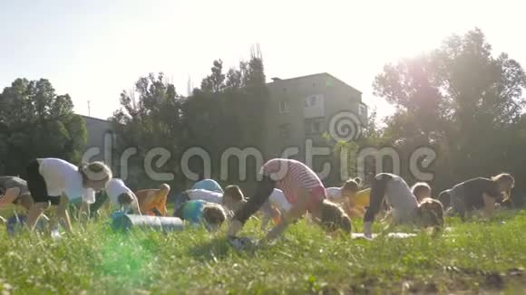 公园里一大群儿童坐在草地上练习瑜伽视频的预览图