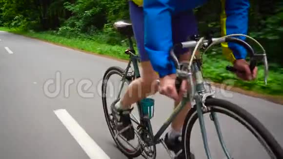 一个中年男子正骑着一辆公路自行车沿着一条森林的行驶视频的预览图
