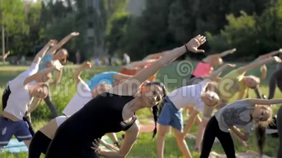 公园里一大群儿童坐在草地上练习瑜伽视频的预览图