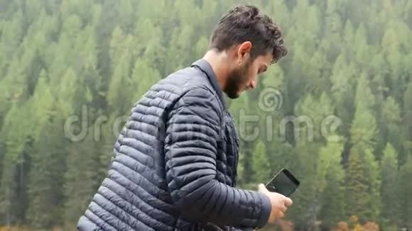 男子用智能手机在湖边拍照视频的预览图