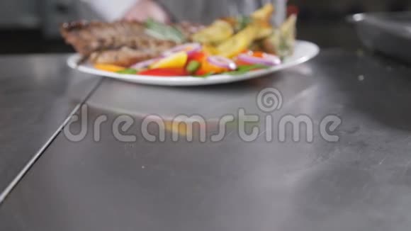 厨师在餐厅做准备用炸土豆和新鲜蔬菜烤羊肉特写视频的预览图