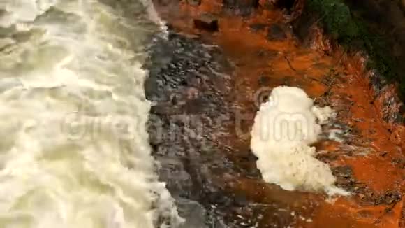 砂岩岩石之间的快速泡沫水肮脏河岸上的橙色沉积物深河床成砂岩块状视频的预览图