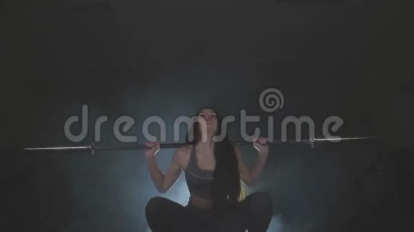 一个年轻女子的全身图像用她肩膀上的一个沉重的杠铃来测试她的力量视频的预览图
