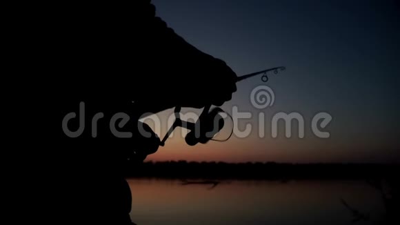 渔人剪影旋转渔轮在背景黄昏日落视频的预览图