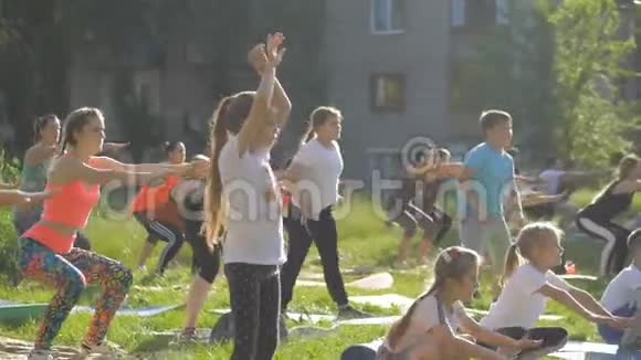 一大群在公园里做瑜伽的孩子坐在草地上视频的预览图