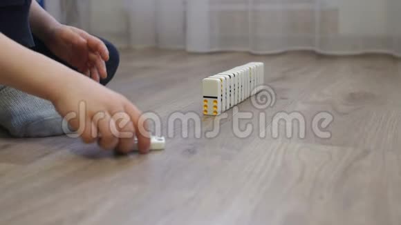 一个孩子在家里地板上玩多米诺骨牌的特写镜头视频的预览图