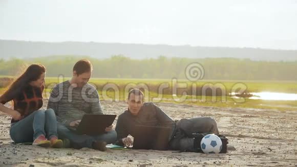 三个朋友在海滩上拿着笔记本电脑慢动作视频视频的预览图