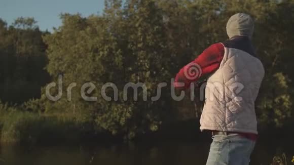 渔夫拿着纺棒在河上钓鱼一个周末的渔夫爱好休闲活跃的夏天和视频的预览图