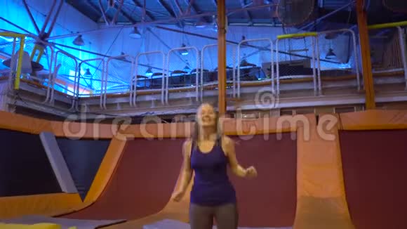 年轻女子运动员在健身公园跳蹦床在室内做运动视频的预览图
