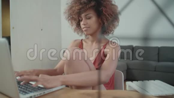 年轻的美国黑人妇女坐在桌旁使用笔记本电脑视频的预览图