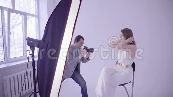 摄影棚时装摄影师摆姿势的专业模特视频的预览图