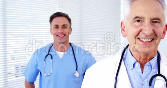 交叉双臂站立的男医生和同事的肖像视频的预览图