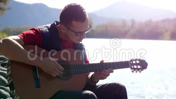 阳光明媚的一天一个人坐在河边弹吉他视频的预览图