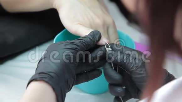 职业美甲师戴着医用黑色面具和黑色手套为女性修指甲视频的预览图