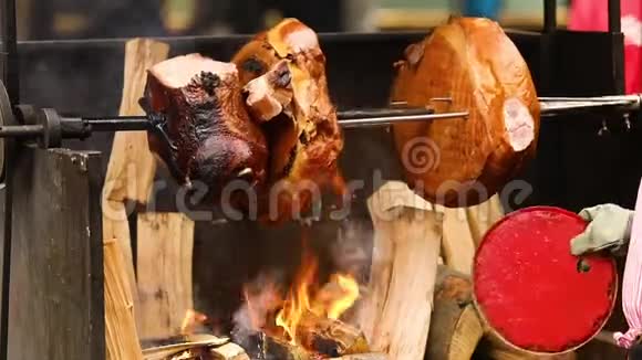 大块美味的猪肉火腿在明火上煮熟街头美食户外食品露营和烹饪视频的预览图