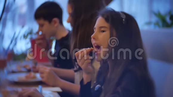 一家群孩子在室内的咖啡馆里吃披萨青少年在咖啡馆慢动作吃快餐视频的预览图