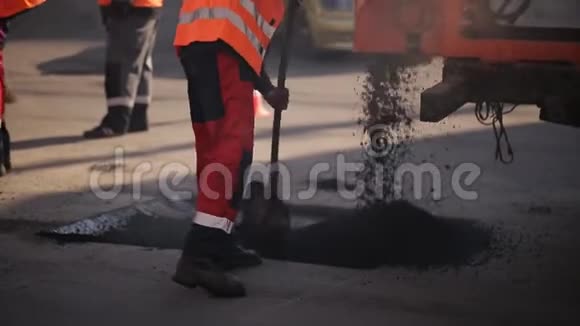 道路施工工人用耙子整平沥青在后道压路机经过时视频的预览图