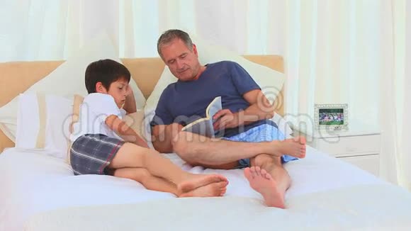 一位祖父和他的孙子在读一本书视频的预览图