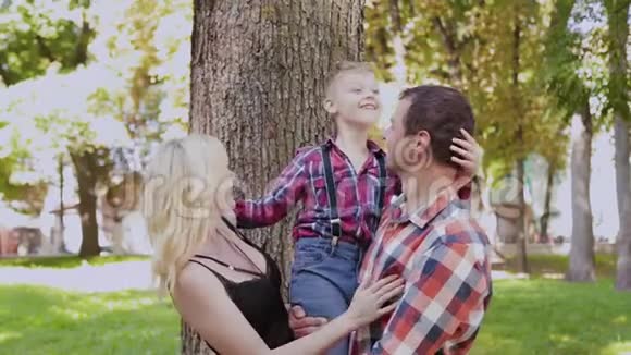 幸福快乐的家庭在公园的树旁拥抱和微笑视频的预览图
