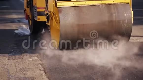 道路施工工人用耙子整平沥青在后道压路机经过时视频的预览图
