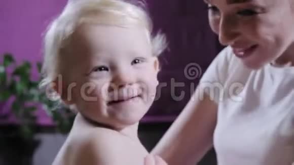婴儿按摩妈妈或治疗师在家给宝宝做足底按摩保健和医药理念金发男孩视频的预览图