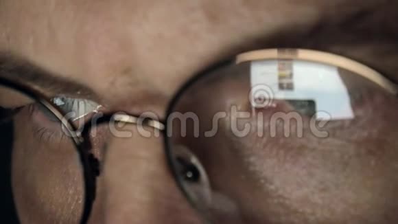 戴眼镜的人工作到深夜他看起来很担心他在面前的电脑屏幕上看到一个特写镜头视频的预览图