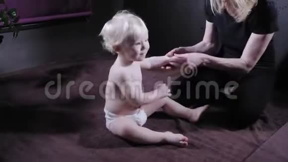 婴儿按摩妈妈或治疗师在家给宝宝做按摩保健和医药理念金发男孩视频的预览图