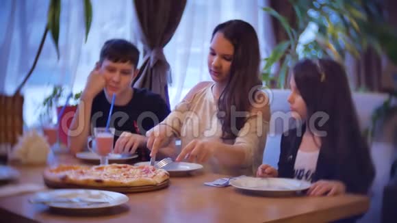 一家群孩子在咖啡馆里吃披萨青少年在室内慢动作咖啡馆吃快餐视频的预览图