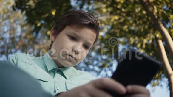 青少年在户外的智能手机上玩电子游戏视频的预览图